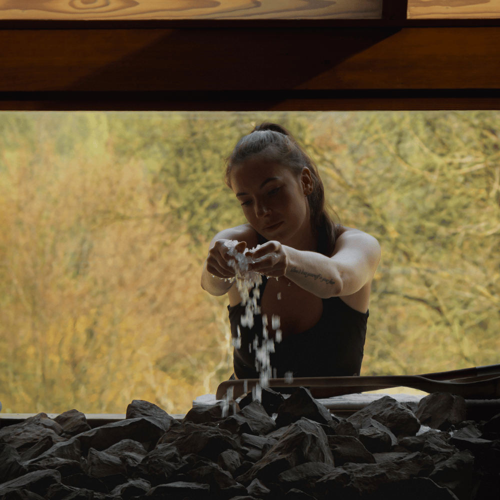vrouw gooit ijs over stenen in sauna