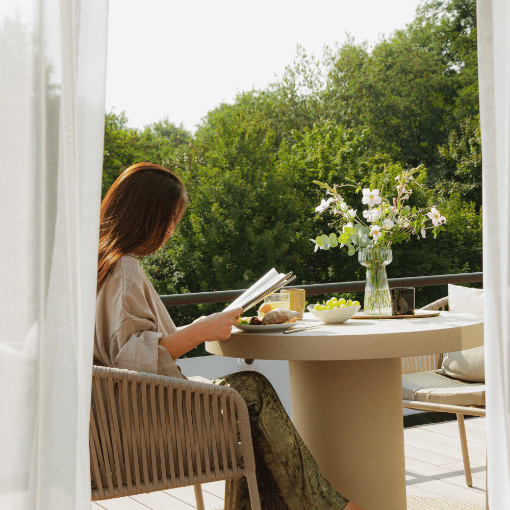 vrouw zit op balkon boek te lezen